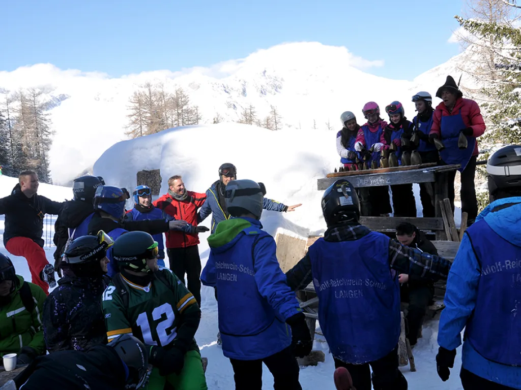 Jugendliche versammeln sich vor der Hütte im Schnee.
